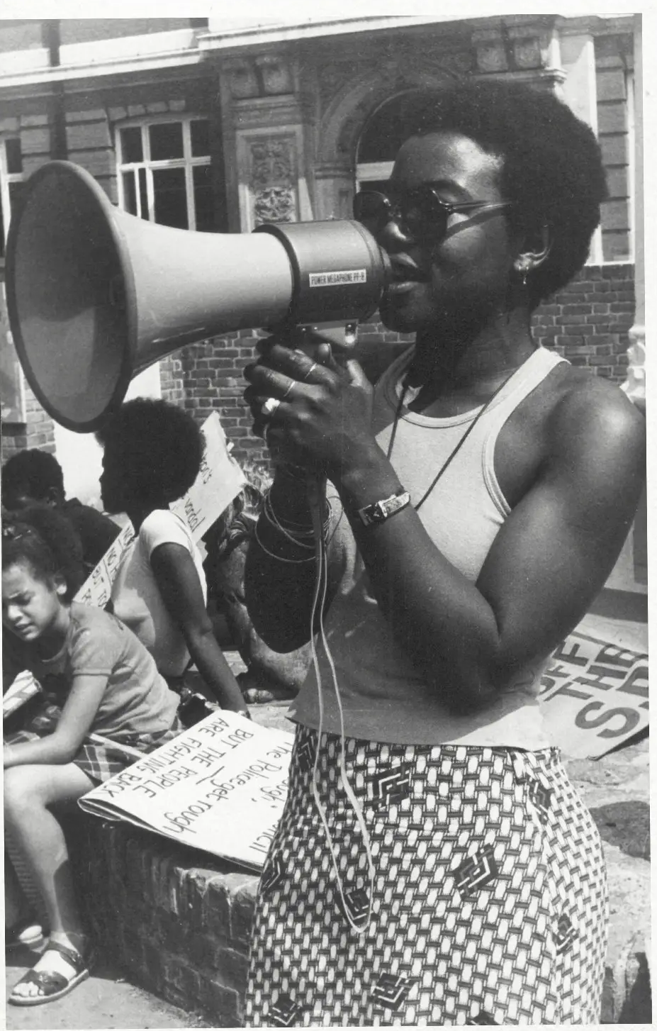 A Black woman looking out confidently over a valley from a hiking trail.